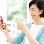 サプリメントを手にスマートフォンで情報を確認する更年期世代の女性